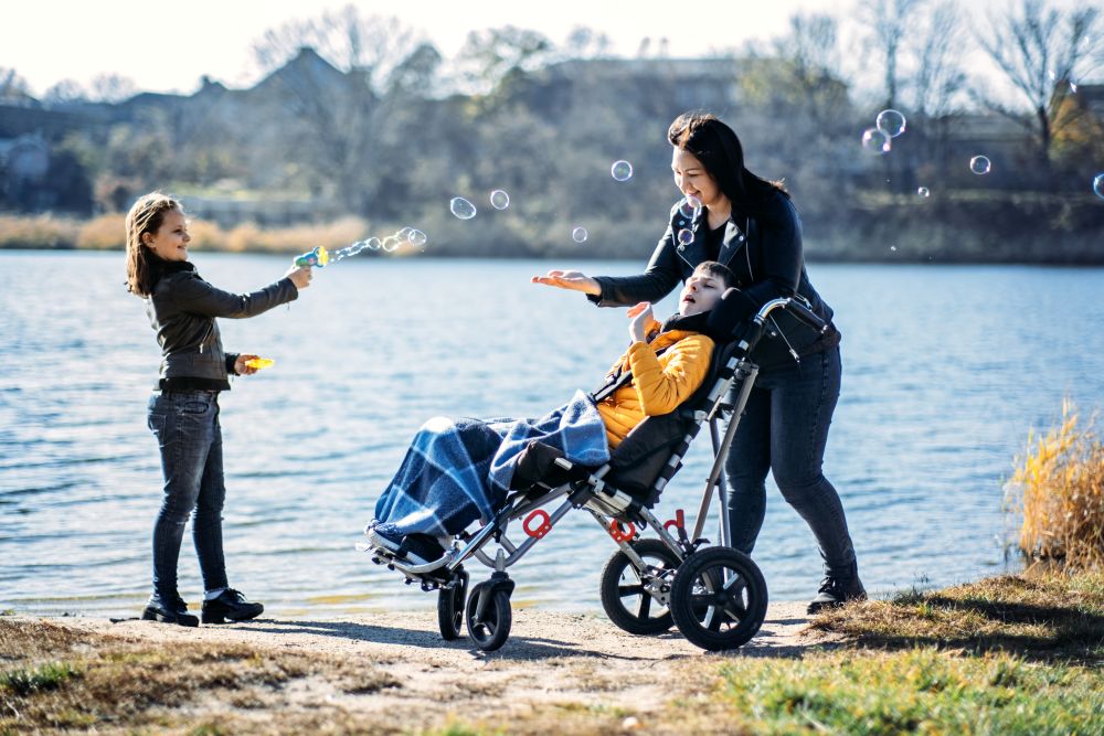 Mother and child in wheelchair playing with bubbles outside